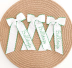 Delilah Bean Stitch Embroidery Font: Three white hair bows with Bulldogs in green bean stitch script