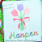 Tulip Bouquet Mini Fill Stitch Embroidery Design: Bouquet of pink and purple tulips tied with a pink bow above the name Harper in green and pink script on white fabric