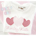 Heart Trio Sketch Stitch Embroidery Design: Three pink sketch stitch hearts above the name Kinley Kate on a white shirt
