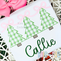 Girls Plaid Christmas Tree Trio with Connecting Bows Sketch Stitch Embroidery Design: Three green plaid Christmas trees linked by pink bows above the name Callie in green on a white shirt