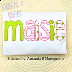 Cupcake Bean Stitch Applique Embroidery Font: The name Maisie in lime green and pink striped and polka dot applique letters on a white shirt