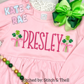 Shamrock Bouquet Mini Fill Embroidery Design: The name Presley in pink between two small shamrock bouquets with pink bows on a pink ruffled shirt
