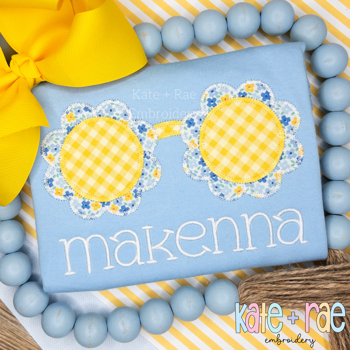 Flower Sunglasses Zigzag Stitch Applique Embroidery Design: Yellow gingham flower shaped sunglasses with blue floral frames above the name makenna on a light blue shirt
