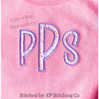 Kinley Satin Stitch Applique Embroidery Font: The letters PPS in purple floral satin applique letters on a pink sweatshirt