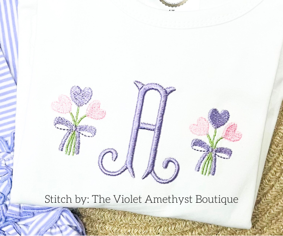 Heart Bouquet Mini Fill Embroidery Design: Purple monogram letter A between two small pink and purple heart bouquets stitched on a white shirt