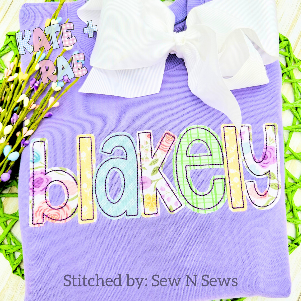 Cupcake Bean Stitch Applique Embroidery Font: The name blakely in pastel floral and gingham applique letters on a purple shirt with a white bow