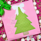 Girls Christmas Tree with Kinley Bow Zigzag Applique Embroidery Design: Green polka dot Christmas tree applique with a white bow beside the name nylah on a pink shirt
