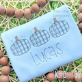 Boy's Plaid Filled Pumpkin Trio Sketch Embroidery Design: Three blue plaid sketch stitch pumpkins above the name Lucas on a light blue shirt