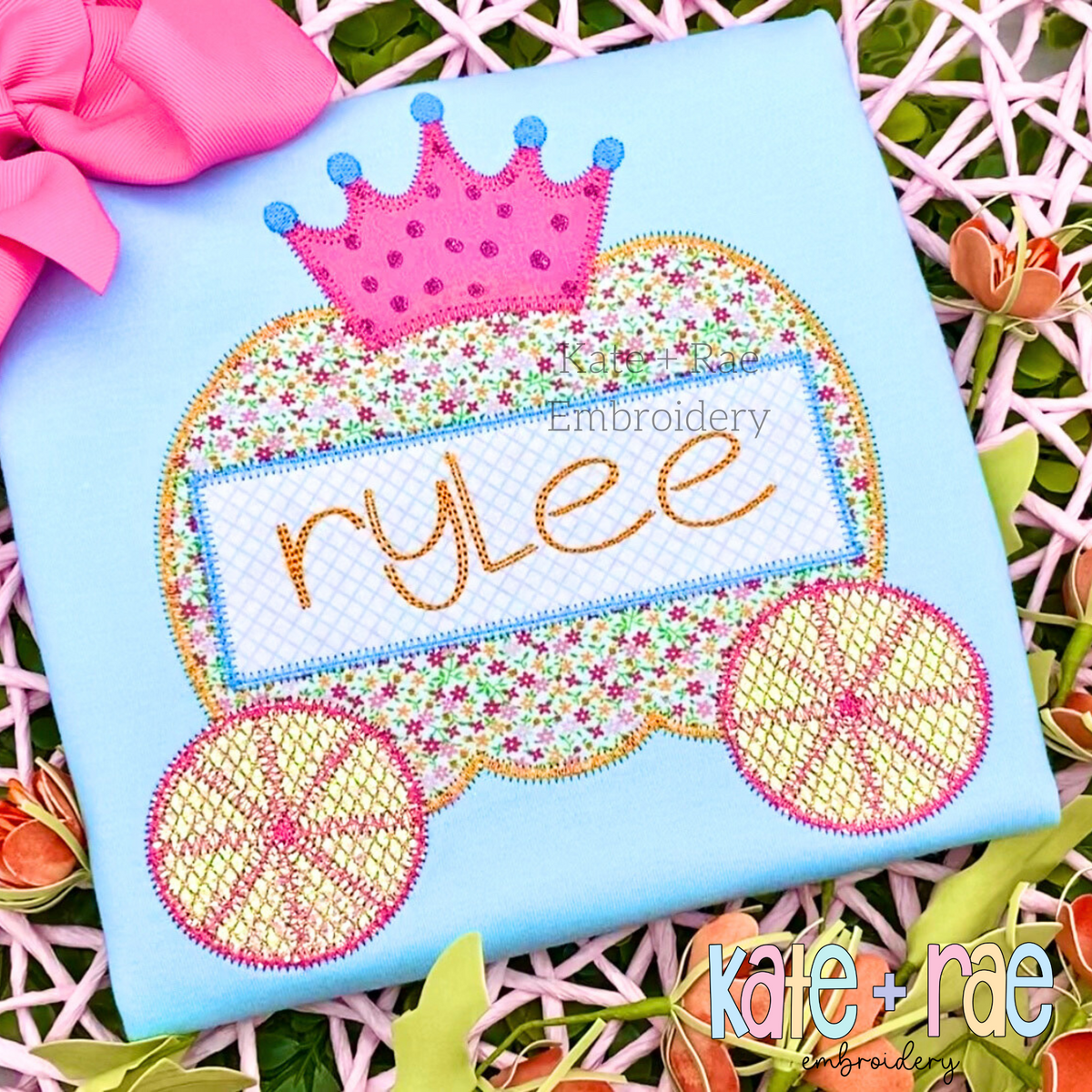 Pumpkin Carriage Zigzag Applique Embroidery Design: Pumpkin carriage applique with a pink crown and the name rylee on a light blue shirt