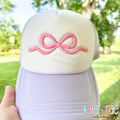 Flowy Bow 3D Puff Satin Stitch Embroidery Design: Pink 3D puff flowy bow on the front of a white and lavender trucker hat