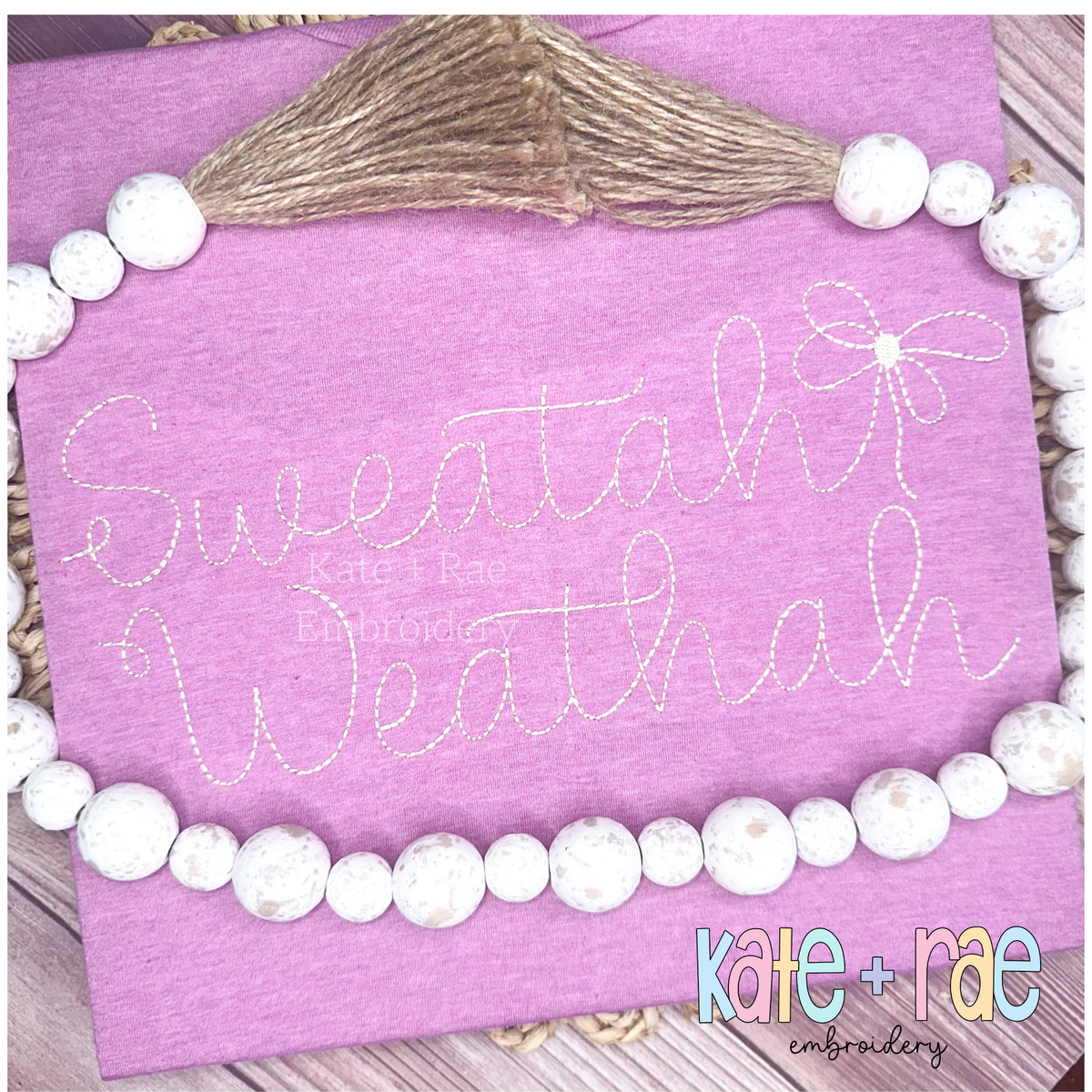 Preppy Bean Stitch Embroidery Font: The words Sweatah Weathah in light pink bean stitch script with a bow on a purple sweatshirt