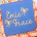 Preppy Satin Stitch Embroidery Font: The name Emie Grace in peach preppy script with bows on a navy shirt