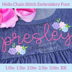 Hello Chain Stitch Embroidery Font: The name presley in pink chain stitch script with pastel floral clusters on a chambray dress