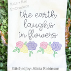 Kinley Floral Sketch Stitch Embroidery Design: The words the earth laughs in flowers in gray script above two pastel flower clusters on a white shirt