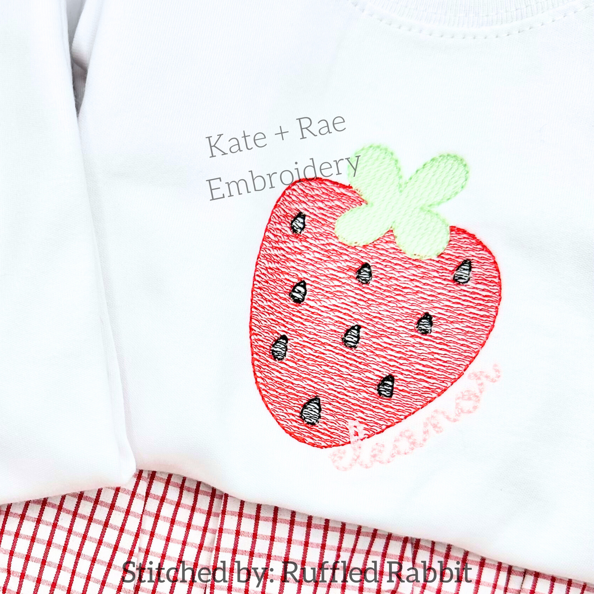 Single Strawberry Sketch Stitch Embroidery Design: Sketch stitch strawberry with a name in pink script on a white shirt over red gingham