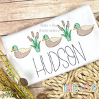 Mallard Ducks and Cattails Sketch Stitch Embroidery Design: Mallard ducks and cattails in sketch stitch above the name HUDSON in black on a white shirt