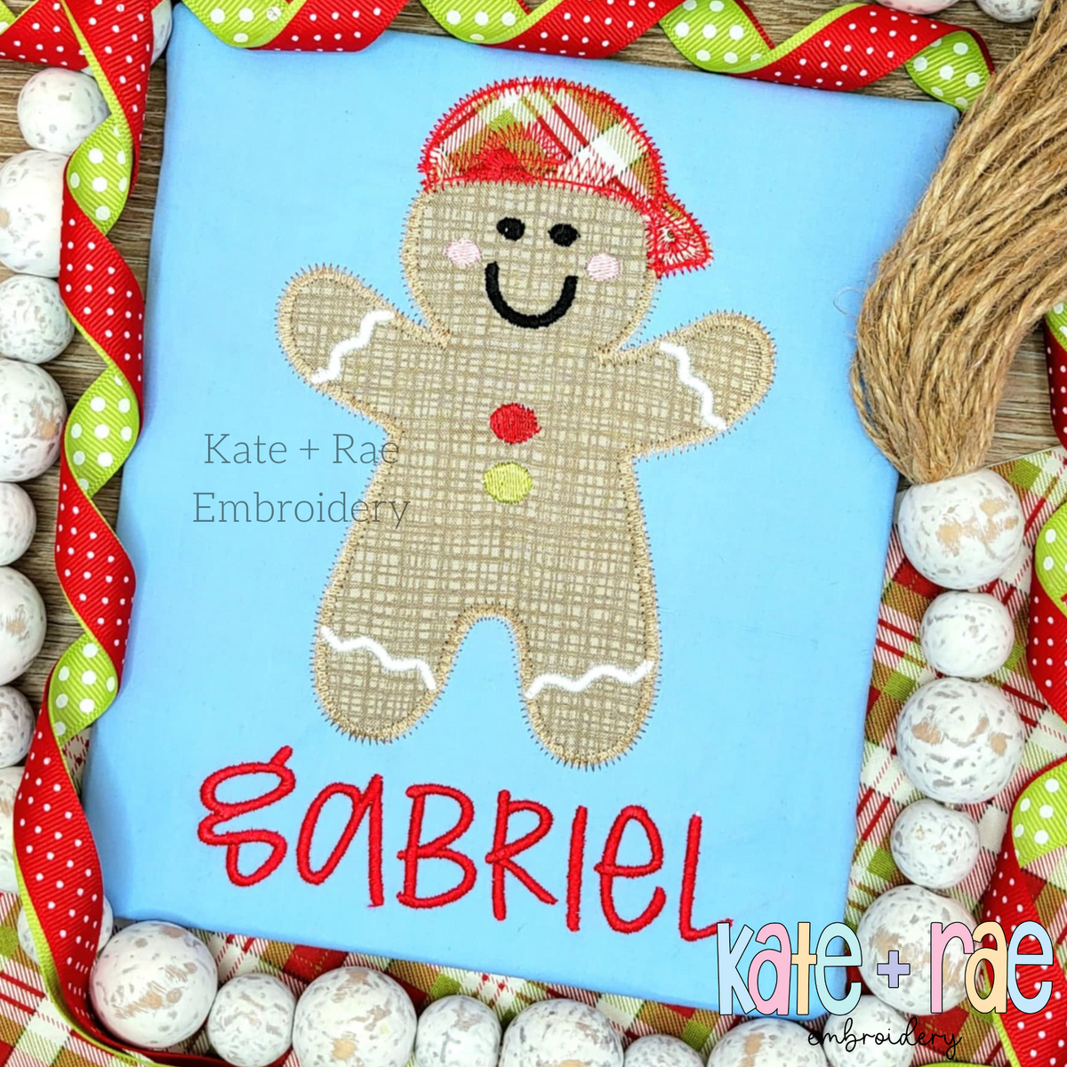 Boy's Gingerbread Man Zigzag Applique Embroidery Design: Gingerbread man applique wearing a plaid cap above the name Gabriel in red on a light blue shirt