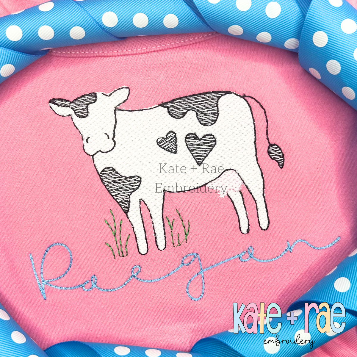 Valentine's Day Cow with Hearts Zigzag Stitch Applique Embroidery Design: Sketch stitch cow with heart shaped spots above the name Raegan in blue script on a pink shirt