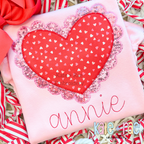 Scalloped Double Heart Zigzag Stitch Applique Embroidery Design: Red heart print applique with a pink sequin scalloped edge above the name annie in pink on a pink shirt