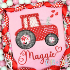 Tractor with Hearts Zigzag Stitch Applique Embroidery Design: Red tractor applique with floral wheels and hearts above the name Maggie in red script on a pink shirt