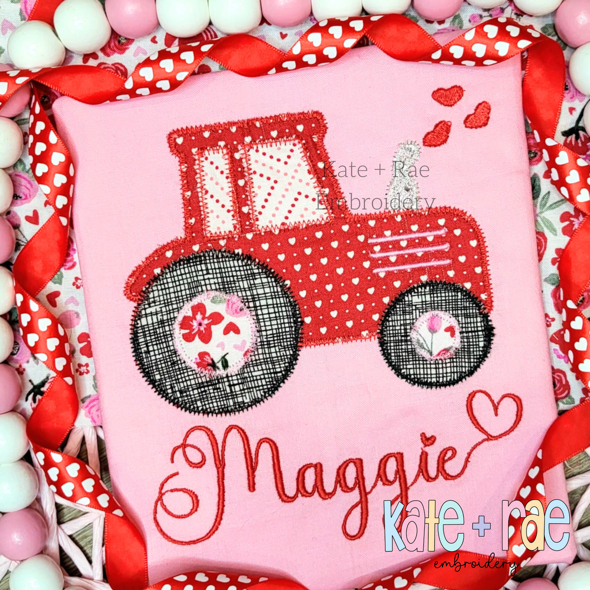 Tractor with Hearts Zigzag Stitch Applique Embroidery Design: Red tractor applique with floral wheels and hearts above the name Maggie in red script on a pink shirt