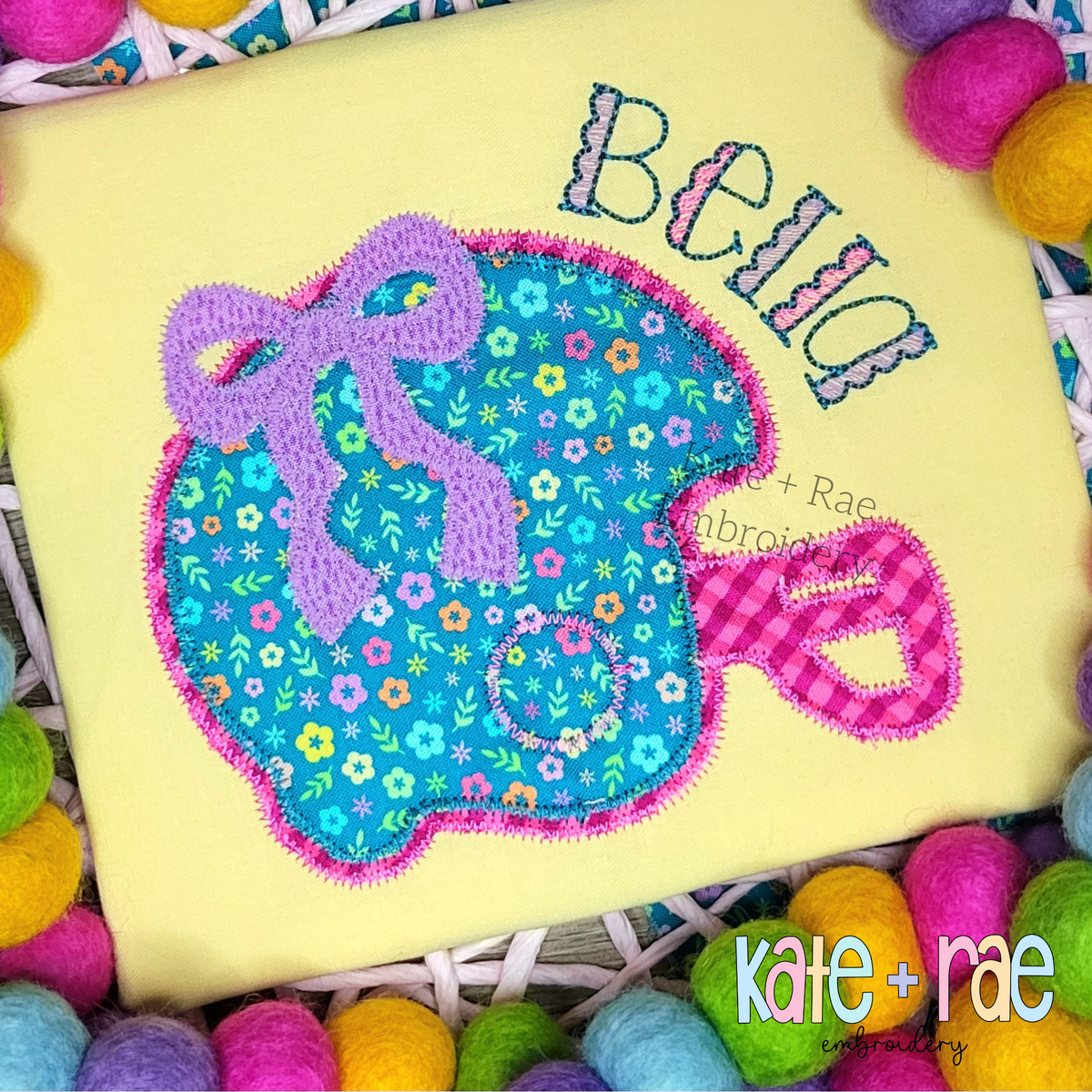 Football Helmet with Bow Double Zigzag Applique Embroidery Design: Teal floral football helmet applique with a purple bow and the name Bella on a yellow shirt