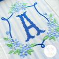 Daisy Floral Crest Satin Stitch Embroidery Design: Blue daisy floral crest around a blue cross stitch letter A on striped fabric
