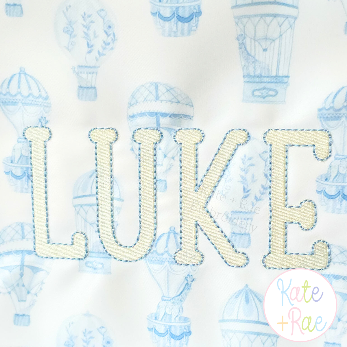 Jellybean Fill Stitch with Bean Border Machine Embroidery Font: Close-up of LUKE in cream Jellybean fill stitch with blue bean border on hot air balloon fabric