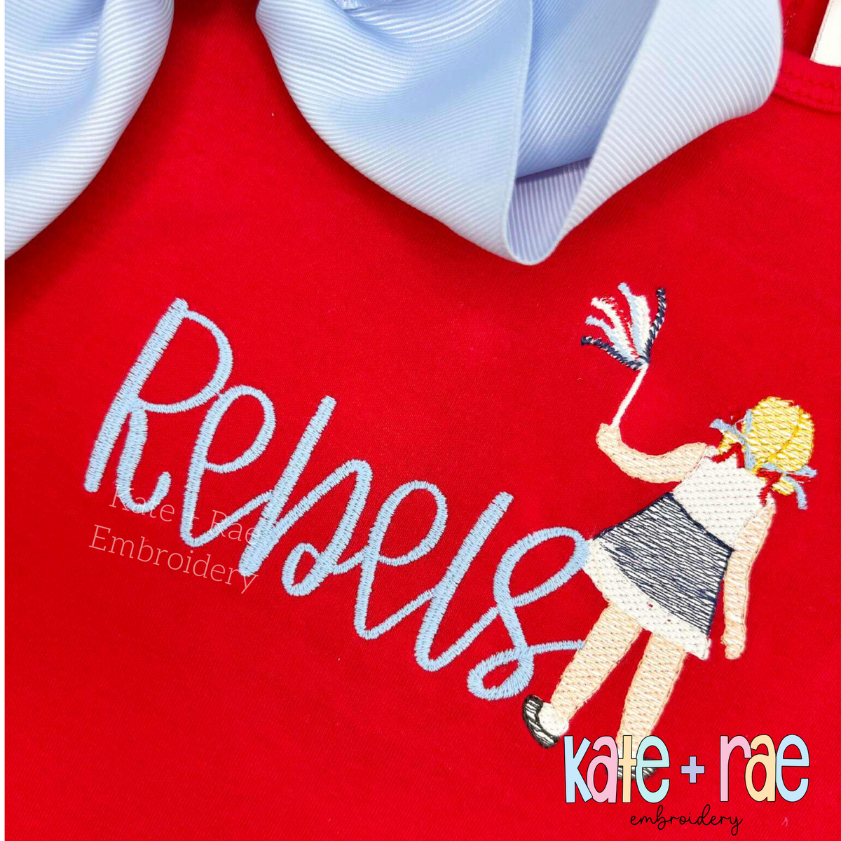 Daisy Handwritten Satin Stitch Embroidery Font: Rebels in light blue handwritten satin script beside a sketch cheerleader on a red shirt