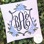 Daisy Floral Crest Satin Stitch Embroidery Design: Blue daisy floral crest around a navy BAE script monogram on white fabric