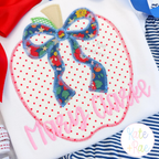A name in pink handwritten script below a floral bow on a polka dot apple applique