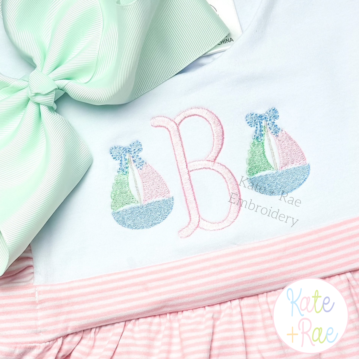 Girl's Sailboat with Bow Mini Fill Stitch Embroidery Design: Two mini sailboats with bows beside a pink letter B on a mint and pink striped outfit