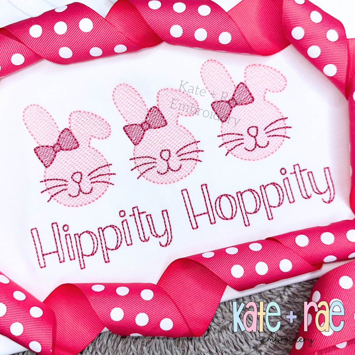 Three pink sketch bunnies with bows above Hippity Hoppity in pink sketch lettering on a white shirt