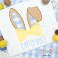 Easter Bunny Ears with Bow Tie Zigzag Stitch Applique Embroidery Design: Tan and blue gingham bunny ears applique with a yellow bow tie above the name Campbell in blue on a white shirt