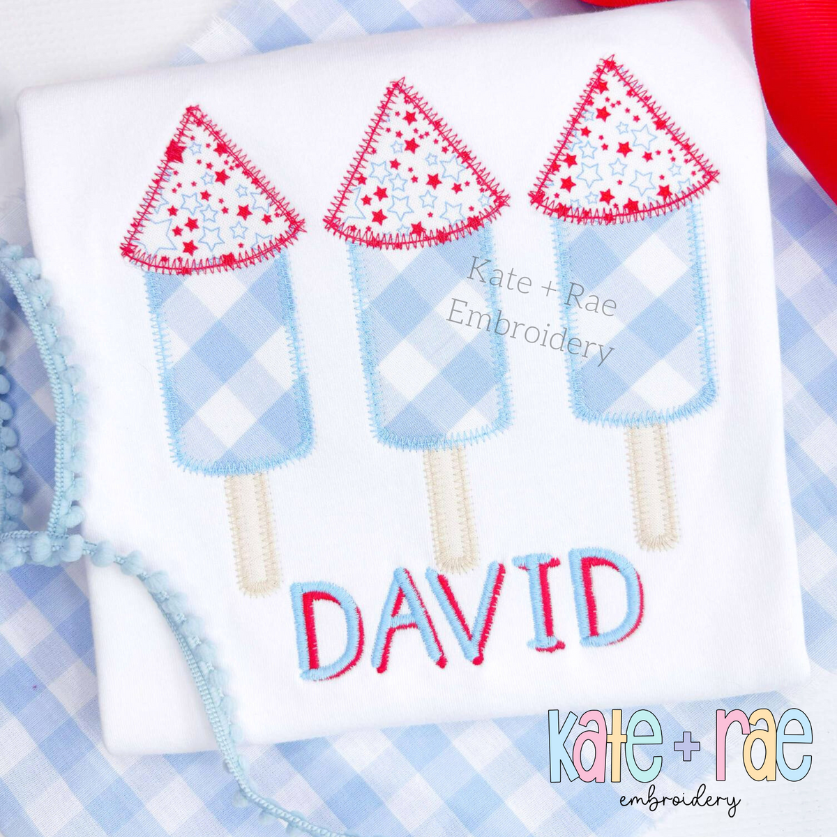 Boy's Firework Trio Zigzag Applique Embroidery Design: Close-up of blue gingham and star print firework appliques above the name DAVID