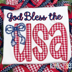 God Bless the USA in navy script and red gingham zigzag applique letters with a blue bow on a white shirt