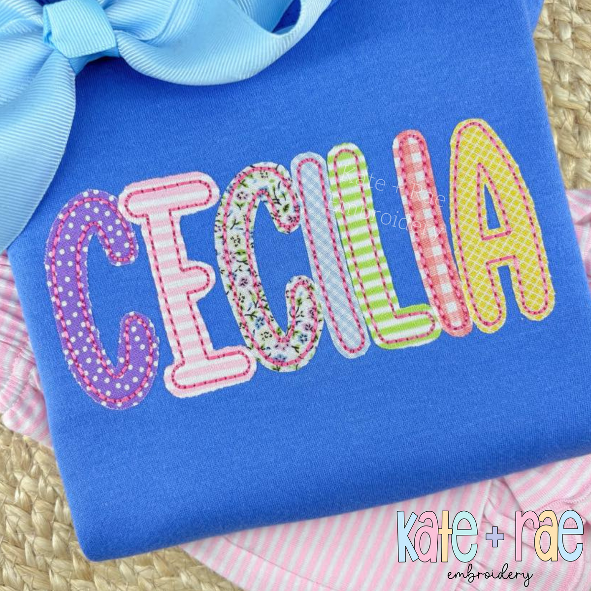 Playground Bean Stitch Applique Embroidery Font: The name CECILIA in patterned bean stitch applique letters on a royal blue shirt