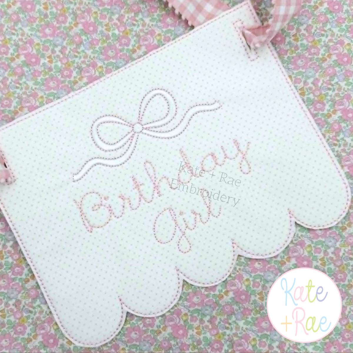 Flowy Long Tail Satin Stitch Bow with Bean Outline Embroidery Design: Pink flowy bow above Birthday Girl in pink script on a scallop bottom banner