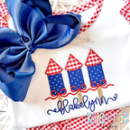 Girl's Firework Trio Zigzag Applique Embroidery Design: Navy polka dot firework appliques with red gingham tops above the name Blakelynn in navy script on a white shirt
