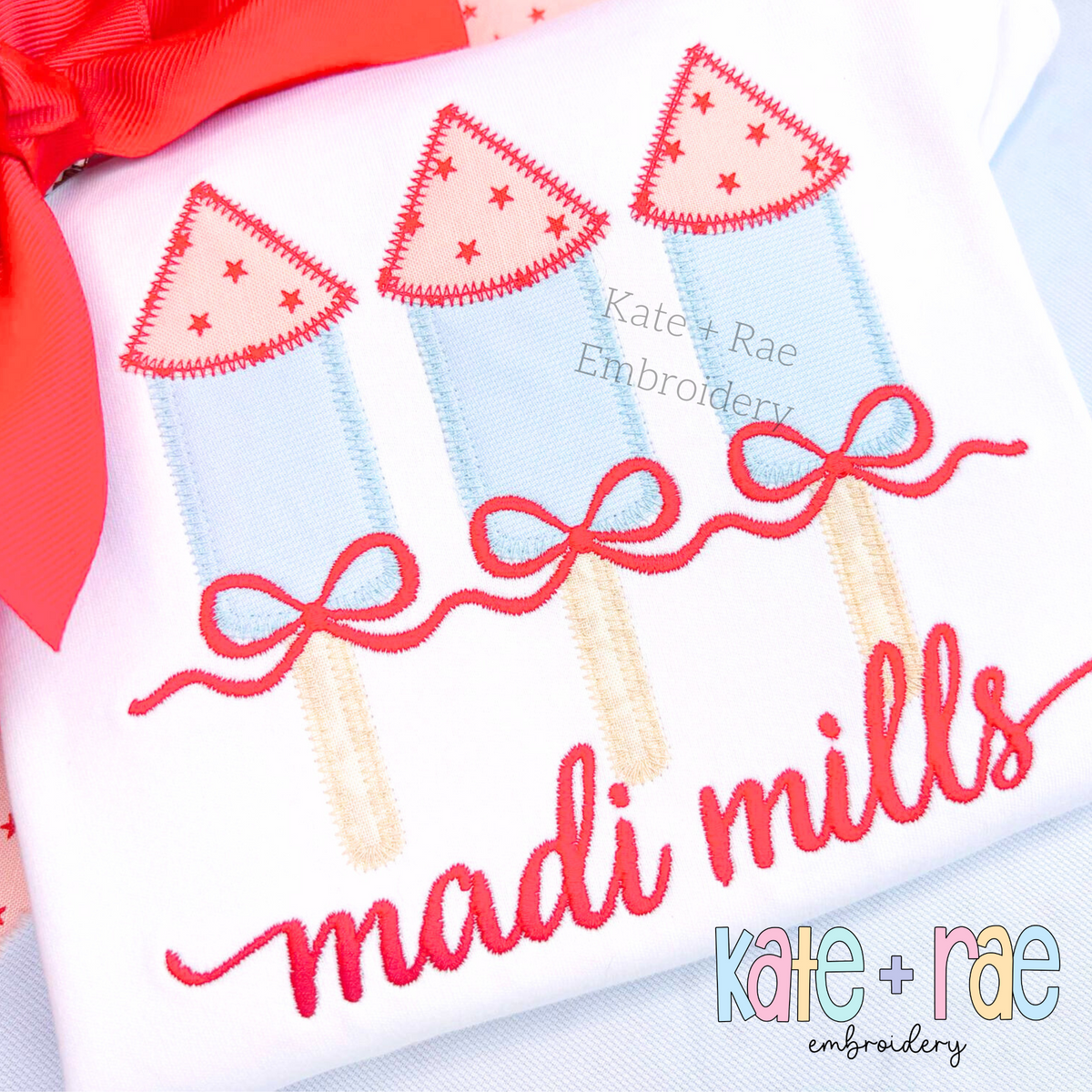 Girl's Firework Trio Zigzag Applique Embroidery Design: Three light blue firework appliques with red star tops and red bows above the name madi mills in red script