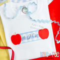 Apple Name Frame Zigzag Applique Embroidery Design: Handwritten name on a blue gingham name plate between two red apple appliques on a white shirt