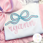 Flowy Longtail Bow Satin Stitch Applique Embroidery Design: Close-up of an aqua and pink flowy bow above the name ryann in pink script