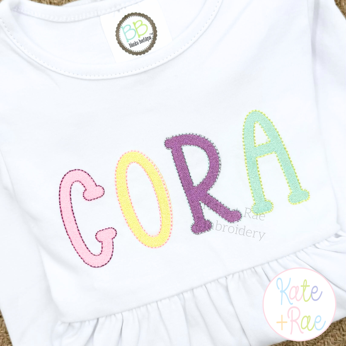 Jellybean Fill Stitch with Bean Border Machine Embroidery Font: CORA in pastel Jellybean fill stitch letters on a white ruffle shirt