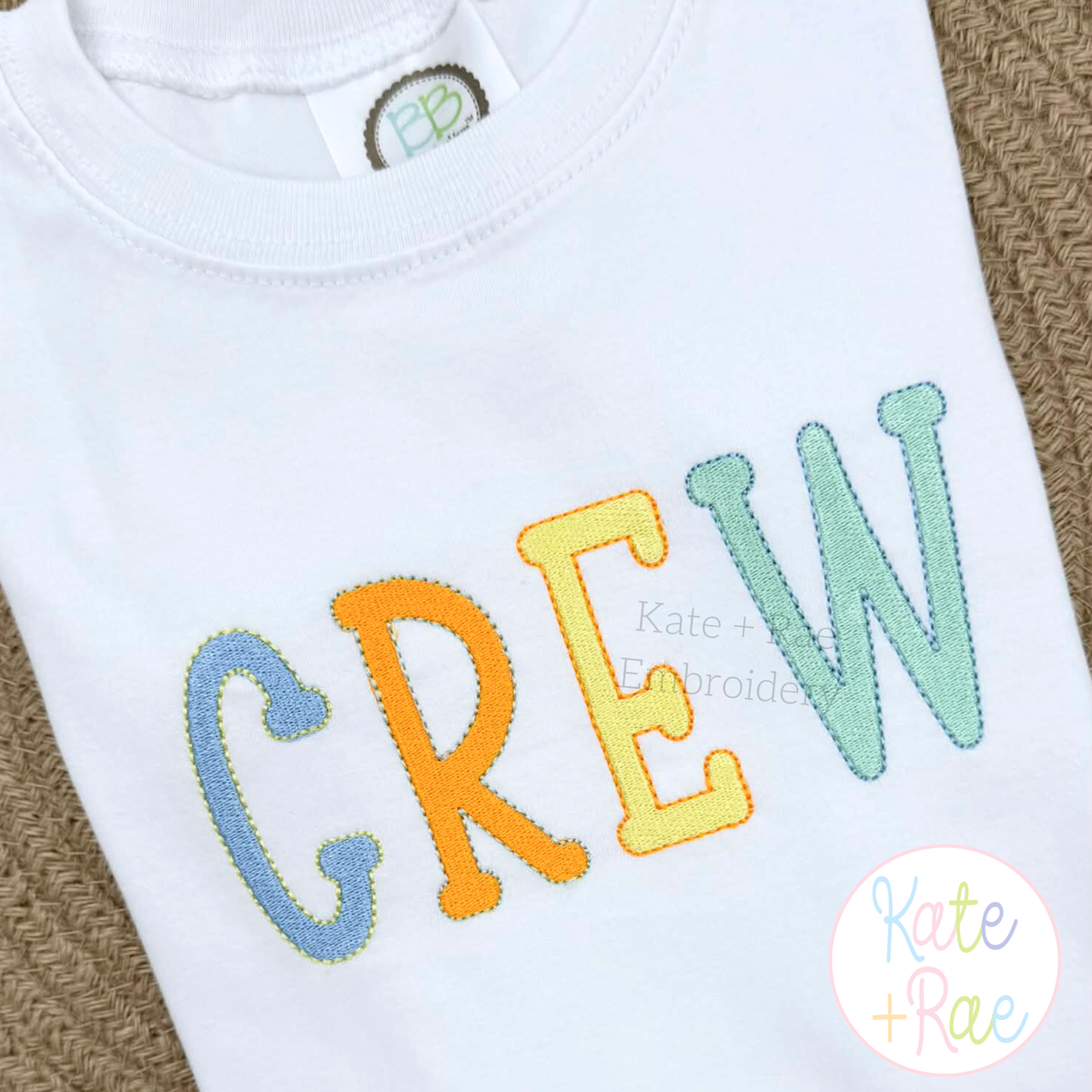 Jellybean Fill Stitch with Bean Border Machine Embroidery Font: CREW in rainbow Jellybean fill stitch letters on a white shirt
