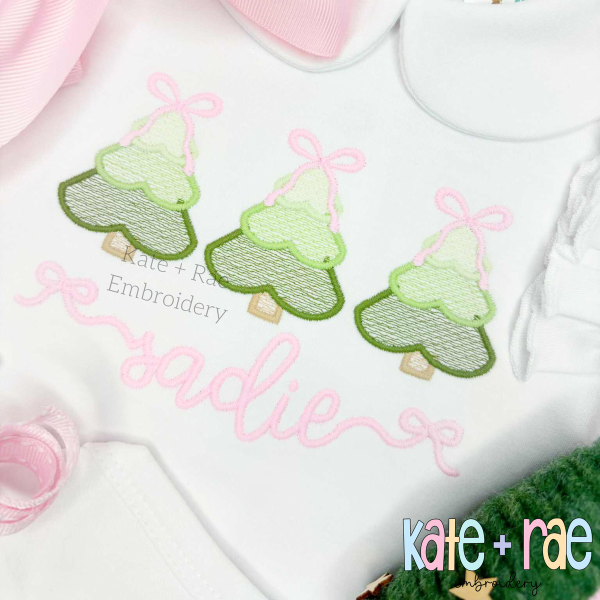 Girls Sketch Stitch Christmas Tree Trio with Satin Stitch Outline Embroidery Design: Close-up of three green sketch Christmas trees with pink bows above the name sadie in pink script