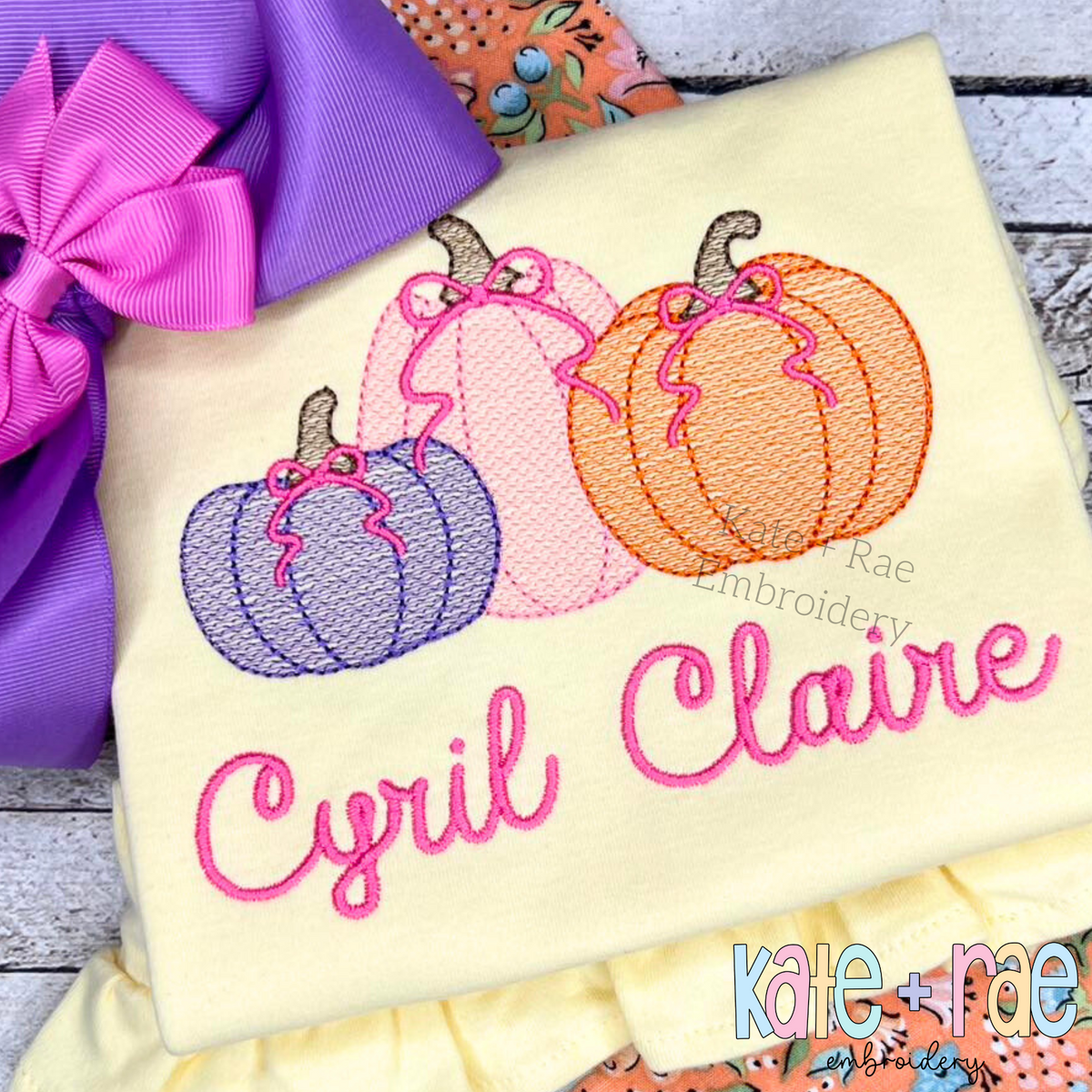 Girl's Fall Pumpkin Trio with Bows Sketch Stitch Machine Embroidery Design: Three sketch stitch pumpkins with pink bows above the name Cyril Claire in pink script on a yellow shirt