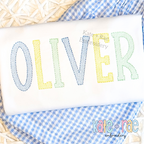 Gracie Sketch Stitch Embroidery Font: The name OLIVER in pastel sketch stitch block letters on a white shirt