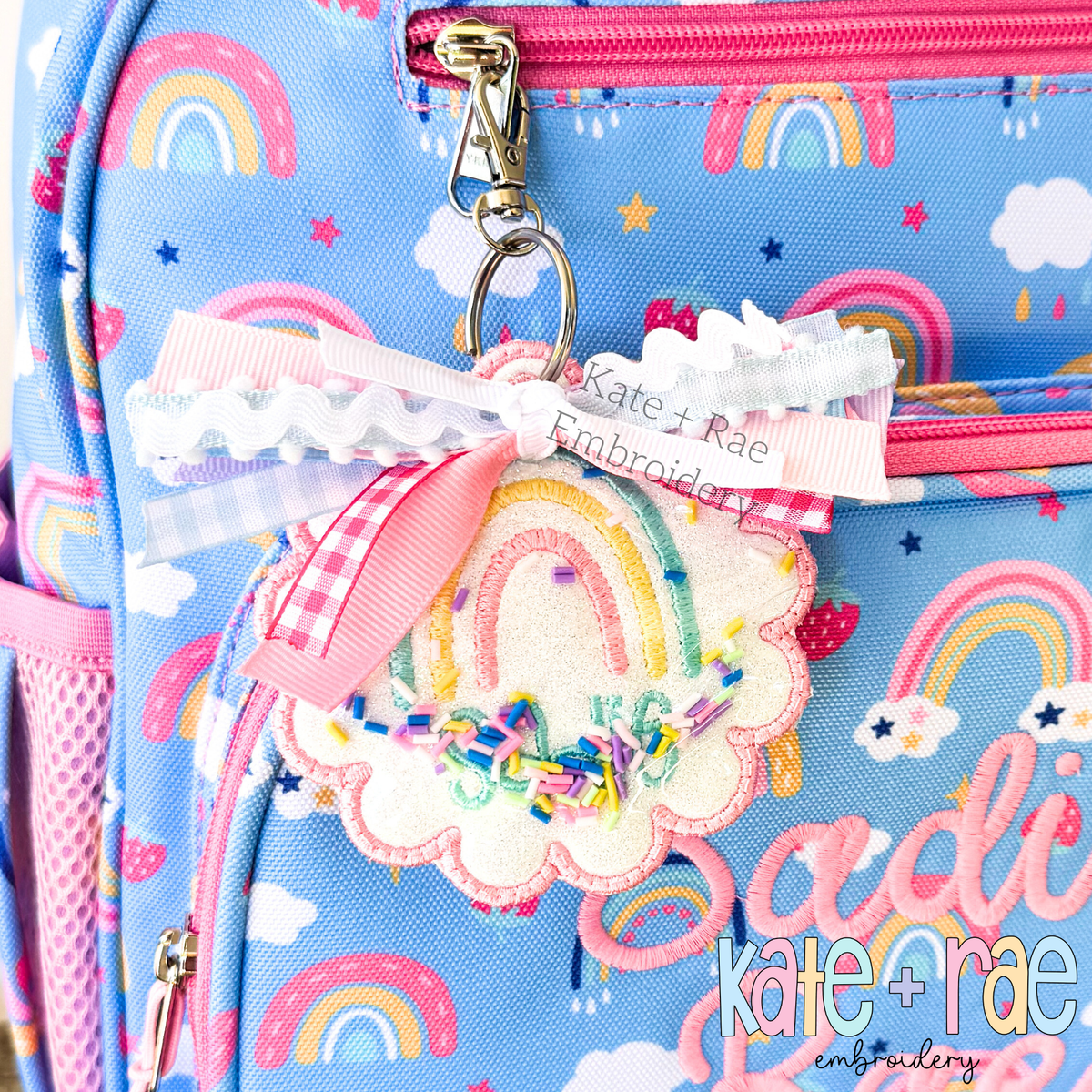 ITH Scalloped Circle Bag Tag Satin Stitch Applique Embroidery Design: Rainbow print backpack with a scalloped rainbow bag tag and the name Sadie Rae in pink