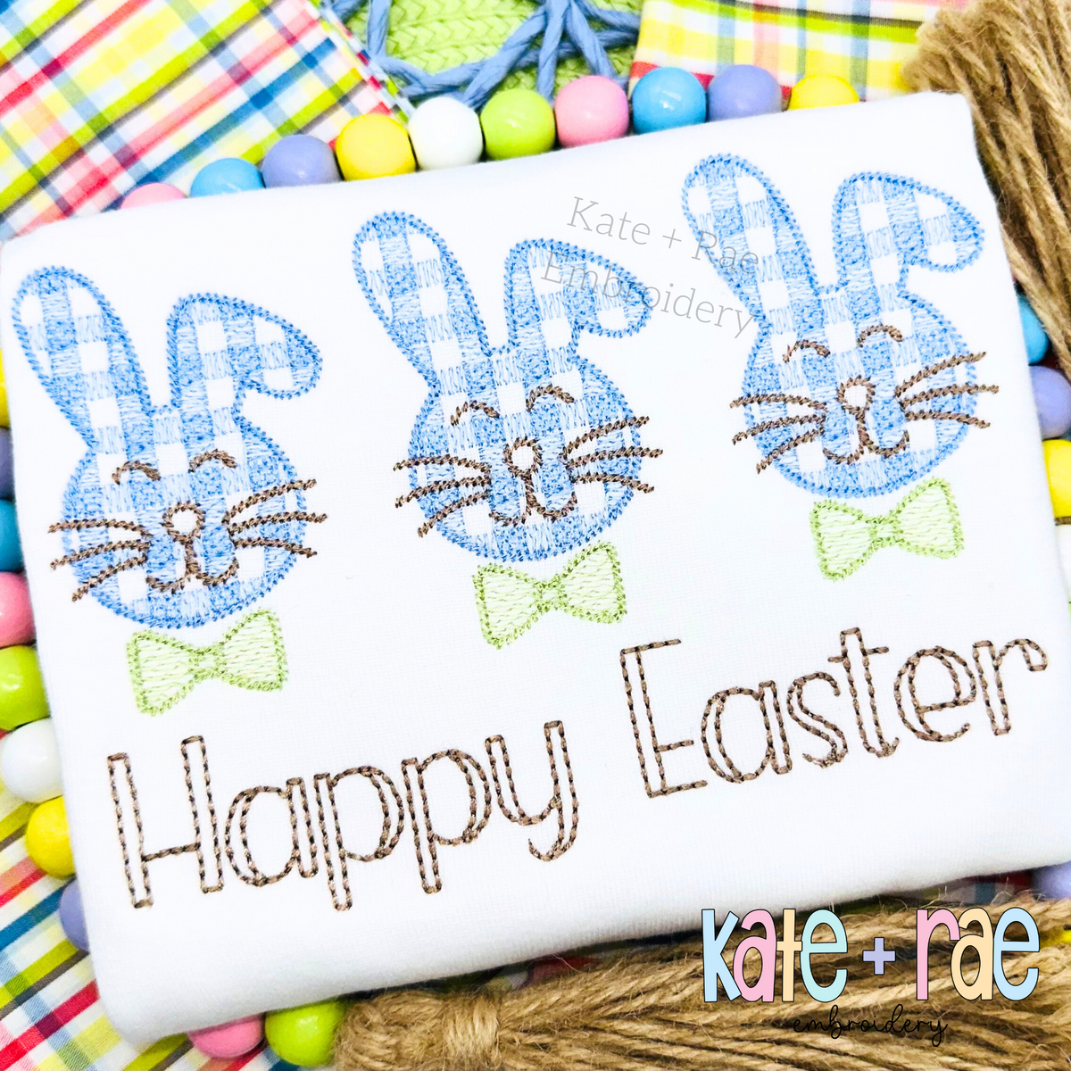 Three blue gingham fuzzy bunnies with green bow ties above Happy Easter in brown sketch lettering on a white shirt