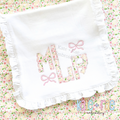 Bow Mini Satin Stitch Embroidery Design: Floral applique monogram with small pink satin bows on a white ruffle blanket